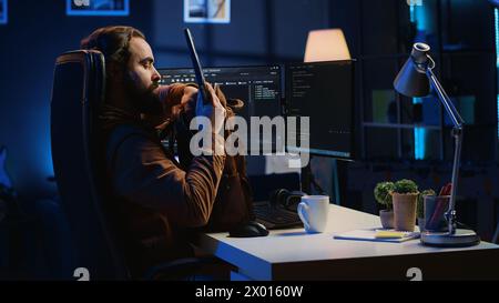 Software designer finishing remote job shift, packing backpack, leaving office after finishing coding project. IT professional putting laptop in bag, sitting up from desk chair, camera A Stock Photo