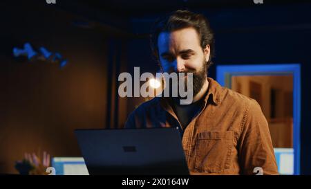 Focused computer scientist writing complex binary code scripts on laptop terminal. Remote IT support worker standing in home office, using programming to safeguard consumer data Stock Photo