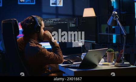 Frenzied programmer suffering from adhd illness, impatiently taping desk with fingers while writing code. Jittery IT expert doing multitasking in office, drinking coffee, listening music, camera A Stock Photo