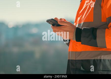 Construction engineer using mobile smart phone on site during inspection, selective focus Stock Photo