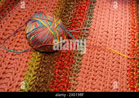 Ball of multi-coloured wool on a hand crocheted blanket Stock Photo