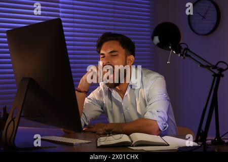 Tired young man working late in office Stock Photo