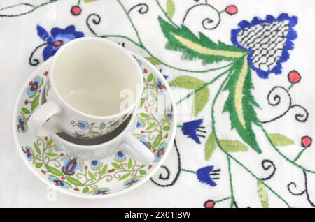 Two cups with Kashubian patterns on a tablecloth with traditional embroidery. Stock Photo