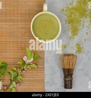 Tea ceremony: matcha, bamboo whisk and twig with leaves, flat lay. Stock Photo