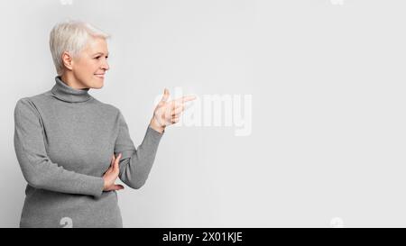 Senior lady gesturing to the side with a smile Stock Photo
