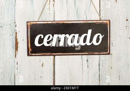 Vintage tin sign on a wooden background - Closed in spanish Stock Photo