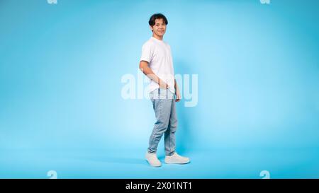 Casual dressed young guy standing profile, blue background Stock Photo