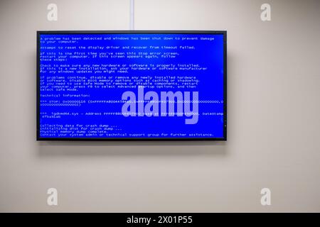 A blue screen of death message displayed on a wall-mounted monitor in an office. Stock Photo