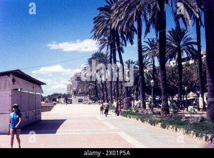 Promenade by Passeig de la Ribera, Sitges, Spain, in August 1965. Seafront path near Platja de la Fragata on the Mediterranean. Hotel Calipolis at far end Stock Photo