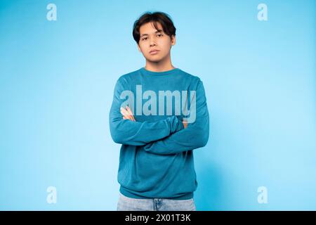 Confident young guy with arms crossed, blue background Stock Photo