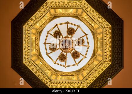 ASWAN, EGYPT - SEPTEMBER 03, 2017: A cupola with elaborately carved ornamentation and a brass chandelier in the 1902 restaurant at the Arabian-inspire Stock Photo