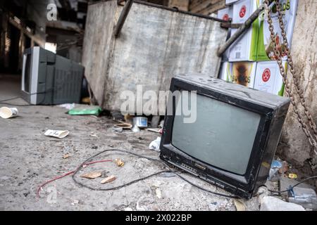 MUHARRAQ, BAHRAIN - FEBRUARY 10, 2018: Defunct cathode ray tube television sets sit abandoned on a concrete floor by a dumpster with other trash. Stock Photo