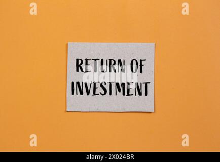 Return of investment words written on ripped paper with orange background. Conceptual symbol. Copy space. Stock Photo