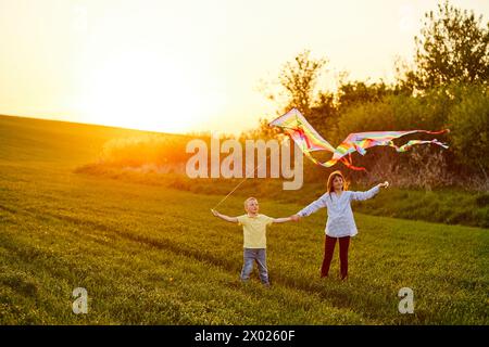 Happy children launch a kite in the field at sunset. Little boy and girl on summer vacation. Stock Photo