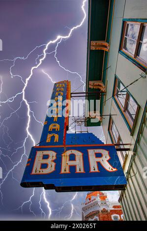 A striking image of a retro bar sign in the heart of Colorado with a powerful lightning storm brewing, capturing the volatile nature of mountain weath Stock Photo
