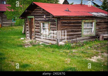 Weathered log cabin, indicative of colorado's rich history, stands in a mountainous landscape, representing the enduring spirit of the heart land's na Stock Photo