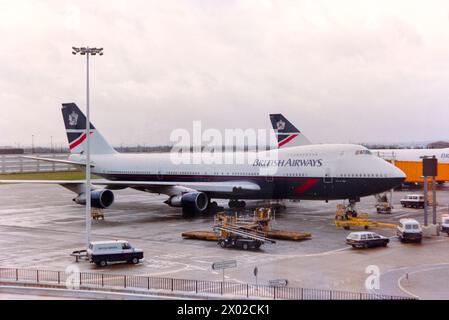 British Airways Boeing 747 Jumbo Jet plane G-BDXH named City of Elgin at London Heathrow Airport in 1988 in the Landor colour scheme, along with similarly painted ground vehicles Stock Photo