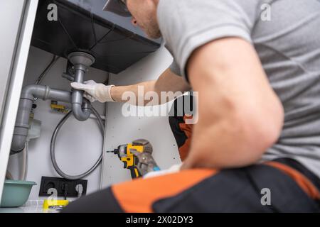Caucasian Plumber Performing Quick Kitchen Sink Drain Fix Stock Photo