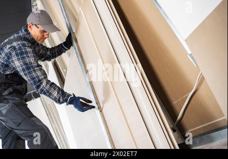 Construction Contractor Worker Marking Cutting Place on a Sheet of a Drywall Panel Stock Photo