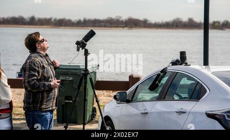 NORWALK, CT, USA - APRIL 8, 2024: Photographer with camera on tripod set up for American Eclipse on Calf Pasture Beach Stock Photo