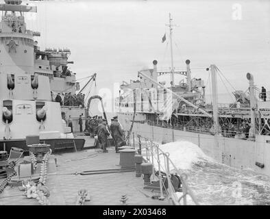 CRUISER REFUELLING AT SEA. SEPTEMBER 1944, ON BOARD HMS JAMAICA AT SEA, REFUELLING FROM A TANKER. - Looking aft as the ships proceed with refuelling still in progress. In the foreground is a rating holding a marked line which enables the navigator watching from the bridge to keep a true course during the operation Stock Photo