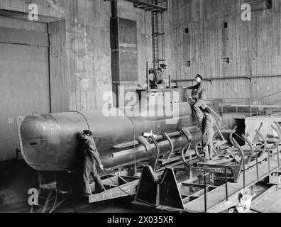 BRITISH NAVY TAKES OVER AT KIEL. 12 MAY 1945, KIEL. THE ROYAL NAVY TRAVELLING OVERLAND FROM OSTEN TOOK OVER THE GERMAN NAVAL PORT AND DOCKYARD AT THE SOUTHERN END OF KIEL BAY. - British naval officers inspecting completed 2-men midget U-boats in gigantic shelter where they arrived in sections and were assembled Stock Photo