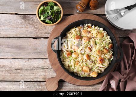 Delicious scallop pasta with onion served on wooden table, flat lay. Space for text Stock Photo