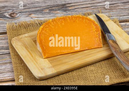slice of French cheese: extra old mimolette, close-up, on a cutting ...