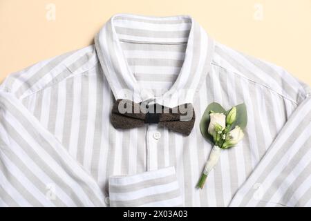 Wedding stuff. Stylish boutonniere, shirt and bow tie on beige background, top view Stock Photo