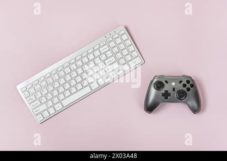 PC keyboard and gamepad on a smooth pink surface Stock Photo