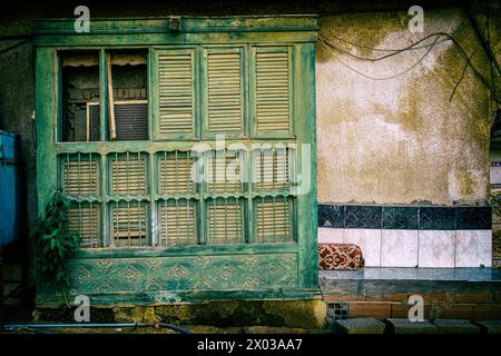 A filtered view of a mashrabiya or traditional carved wooden screen covering an air conditioner unit on the exterior of an arabian house in the Middle Stock Photo