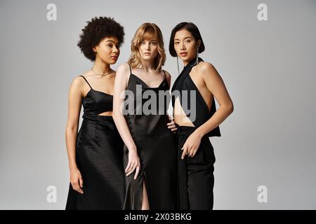 A group of beautiful women from diverse backgrounds standing together in elegant spring attire against a grey studio background. Stock Photo