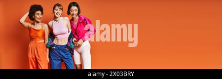 Diverse group of women, including Caucasian, Asian, and African American, standing side by side against an orange background. Stock Photo