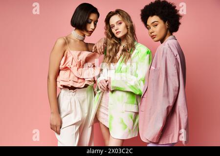 A diverse group of three women standing together, representing multiculturalism and beauty, against a pink studio background. Stock Photo