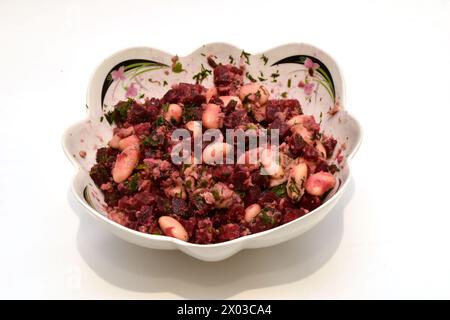 A salad of boiled vegetables, beets, carrots, potatoes, beans and boiled tuna lies in a deep plate, top view. Stock Photo