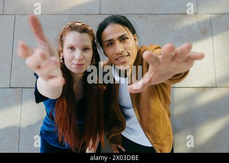 Smiling couple extending hands towards camera with a friendly gesture. Stock Photo