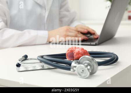 Endocrinologist working at table, focus on stethoscope and model of thyroid gland Stock Photo