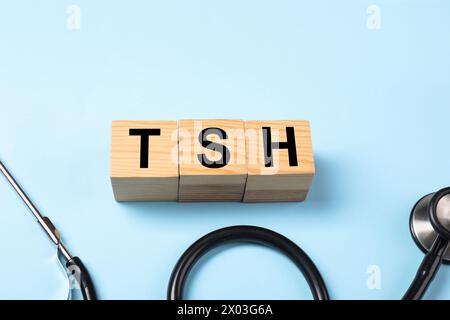 Endocrinology. Stethoscope and wooden cubes with thyroid hormones on light blue background. Space for text Stock Photo