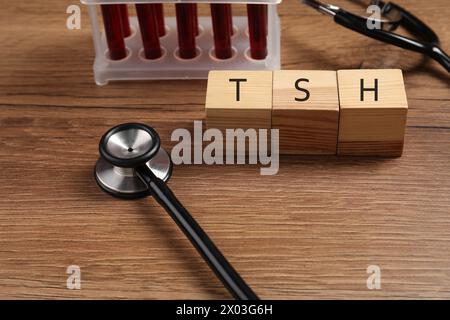 Endocrinology. Stethoscope, cubes with thyroid hormones and blood samples in test tubes on wooden table Stock Photo