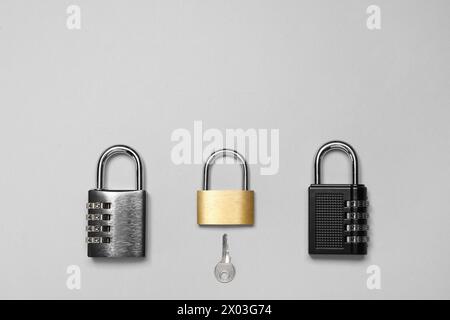 Different padlocks and key on grey background, flat lay. Space for text Stock Photo
