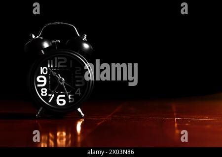 Black retro alarm clock on wooden table Stock Photo