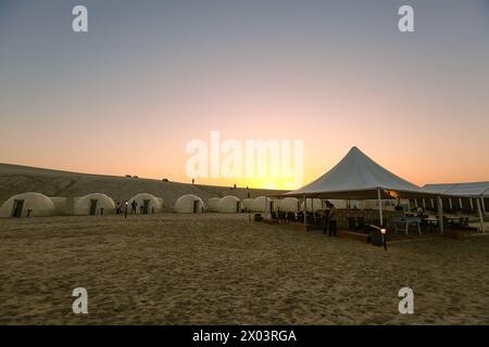 Tents at QIA desert camp at Inland Sea in Persian Gulf at sunset sky. Middle East, Arabian Peninsula. Inland sea is a major tourist destination. Stock Photo