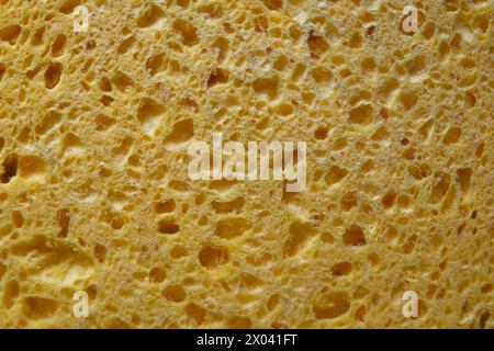 Texture of a yellow cellulose sponge, close-up. Background with holes. Stock Photo