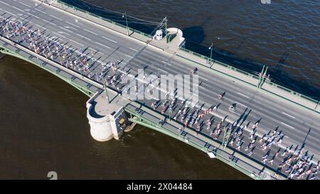 Aerial View of Marathon Runners on a Bridge Crossing a River. A city marathon, a crowd of athletes running across the bridge, an active lifestyle. Stock Photo