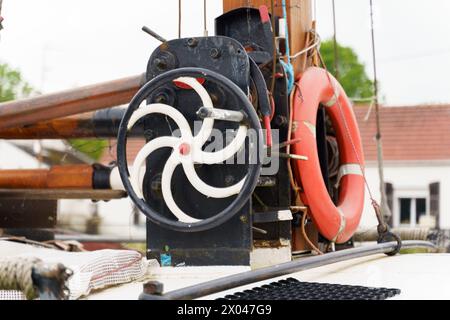 Detailed view of a boats steering wheel mounted on the vessel, showcasing navigation equipment used for controlling the direction of the boat. Stock Photo