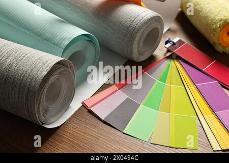 Different wallpaper rolls and color palette samples on wooden table, closeup Stock Photo