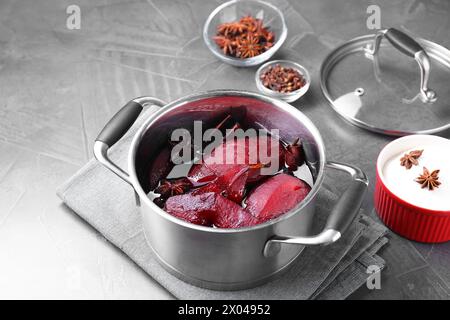 Tasty red wine poached pears and spices in pot on grey table Stock Photo