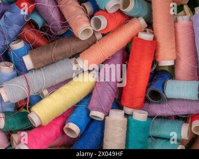 Many colorful threads on spools in disarray Stock Photo