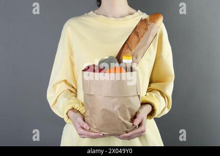 Humanitarian aid. Woman with food products for donation on grey background, closeup Stock Photo