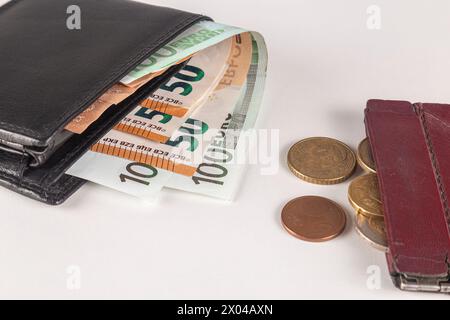 Leather wallet with euro banknotes next to an old wallet with euro coins. Close up. Stock Photo